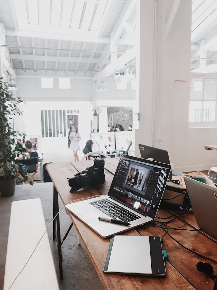 creative A bright, modern workspace featuring laptops, a camera, and a drawing tablet in an indoor office.